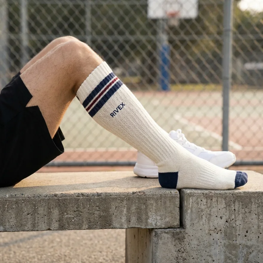 Custom cream below-knee socks with navy stripes and a RIVEX logo, worn on a basketball court