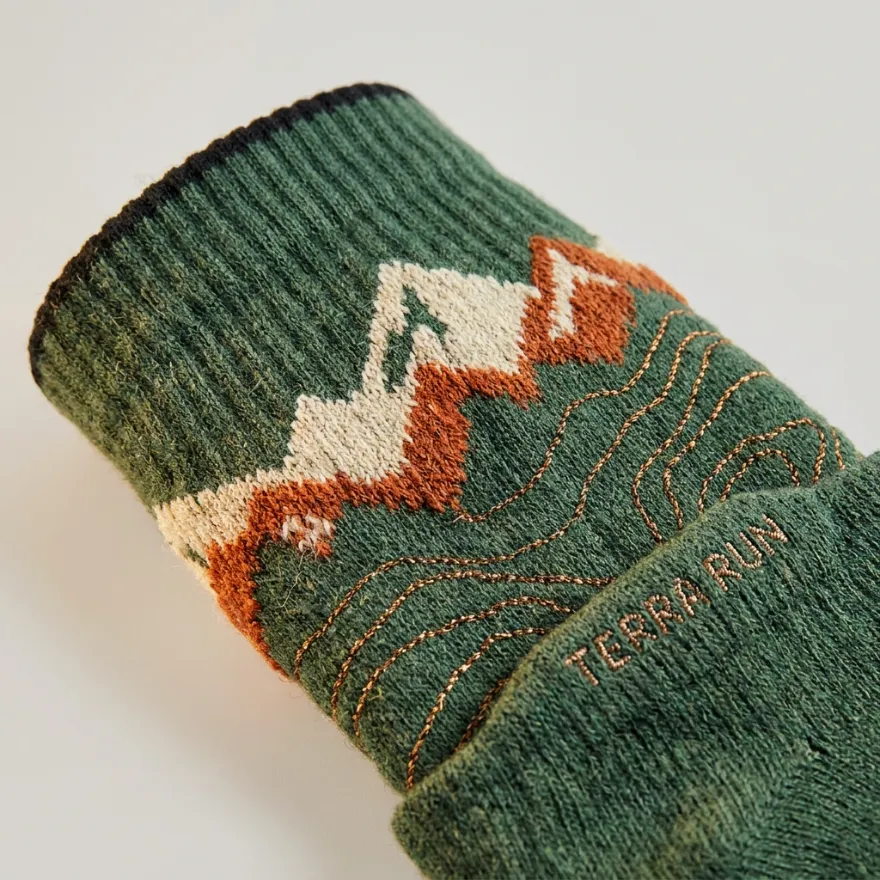 Close-up of custom green below-knee socks with a mountain pattern and a woven TERRA RUN logo