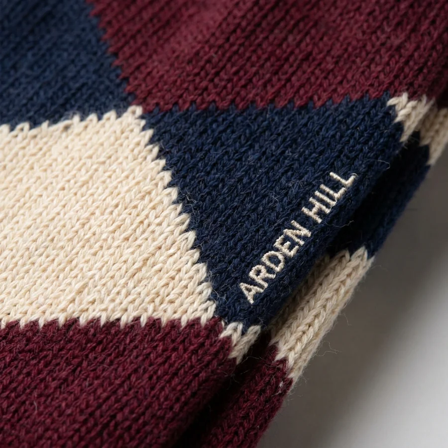 Close-up of custom navy, burgundy and cream argyle dress socks with a woven ARDEN HILL logo