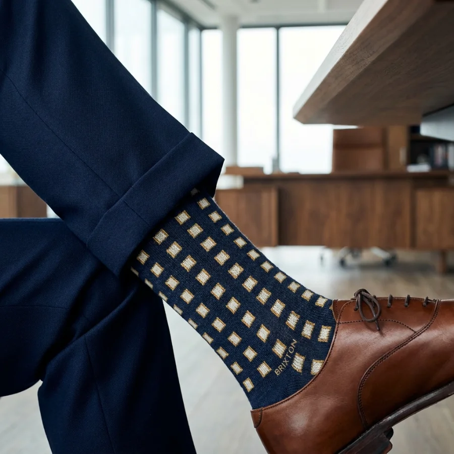 Custom navy and gold patterned dress socks worn with a navy suit and brown shoes in an office